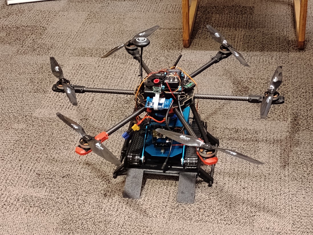 Hexacopter with the tracked ground robot docked on the ramp, sitting on carpet